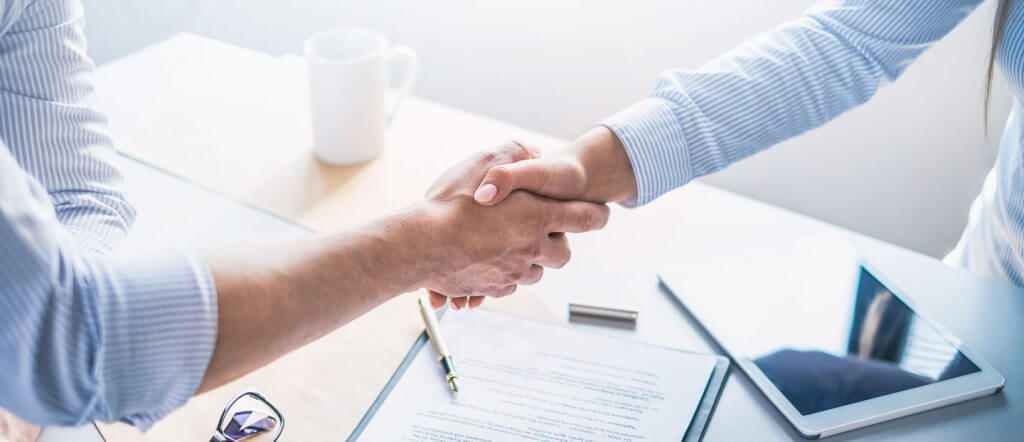 Close-up of a handshake over a signed contract, symbolizing MD ELEKTRONIK's commitment to customer orientation and strong partnerships in the automotive industry.