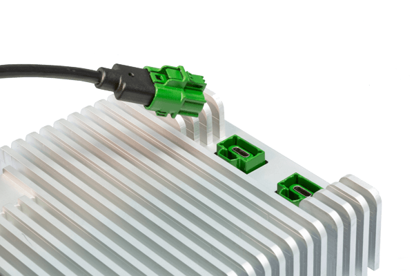 Green connector plugged into a silver aluminum heat sink, showcasing MD ELEKTRONIK's innovative thermal management technology for automotive electronics